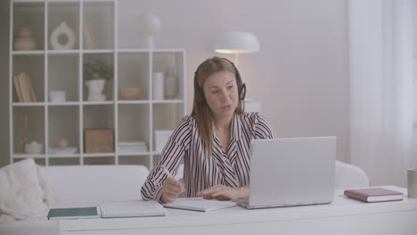 Eine-Junge-Frau-Arbeitet-Von-Zu-Hause-Aus-Und-Führt-Online-Verhandlungen-Per-Video-Chat-Am-Laptop-über-Kopfhörer-Mit-Mikrofon